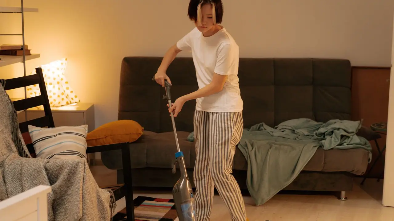 Empleada del hogar pasando la aspiradora en una vivienda.