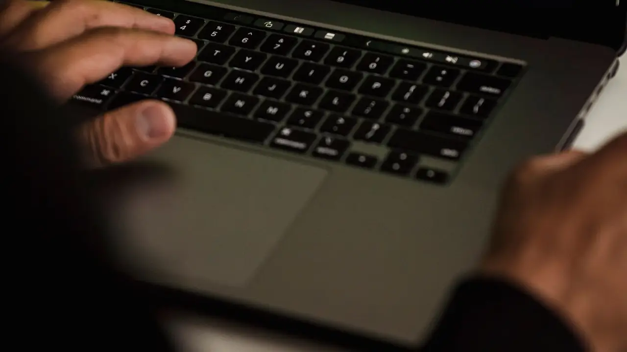 Certificado ciberseguridad. Persona escribiendo código en un portátil con datos en pantalla.