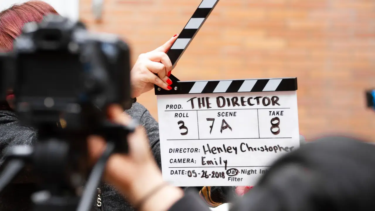 Persona sujetando una claqueta de cine en un rodaje.